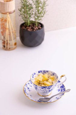 Lezzetli peynirli kek ve çay fincanında yapılmış kivi meyvesi.