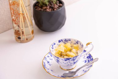 Lezzetli peynirli kek ve çay fincanında yapılmış kivi meyvesi.