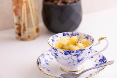 Lezzetli peynirli kek ve çay fincanında yapılmış kivi meyvesi.