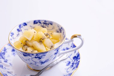 Lezzetli peynirli kek ve çay fincanında yapılmış kivi meyvesi.