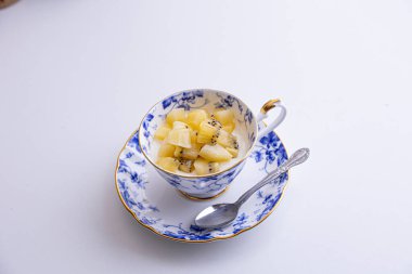 Lezzetli peynirli kek ve çay fincanında yapılmış kivi meyvesi.