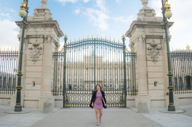 Şehir yaşam tarzı, genç mutlu ve güzel Asyalı bir kadının güzel sonbahar elbiseli portresi Madrid şehri turunun keyfini çıkarıyor sarayın demir kapısında rahat ve neşeli. 