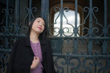 Şehir yaşam tarzı, genç mutlu ve güzel Asyalı bir kadının güzel sonbahar elbiseli portresi Madrid şehri turunun keyfini çıkarıyor sarayın demir kapısında rahat ve neşeli. 