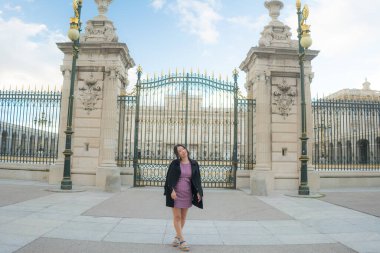 Şehir yaşam tarzı, genç mutlu ve güzel Asyalı bir kadının güzel sonbahar elbiseli portresi Madrid şehri turunun keyfini çıkarıyor sarayın demir kapısında rahat ve neşeli. 