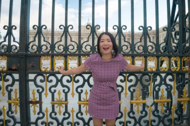 Şehir yaşam tarzı, genç mutlu ve güzel Asyalı bir kadının güzel sonbahar elbiseli portresi Madrid şehri turunun keyfini çıkarıyor sarayın demir kapısında rahat ve neşeli. 