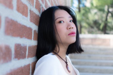 Şehir parkında havalı poz veren genç, mutlu ve güzel Asyalı bir Koreli kadının hayat tarzı portresi.