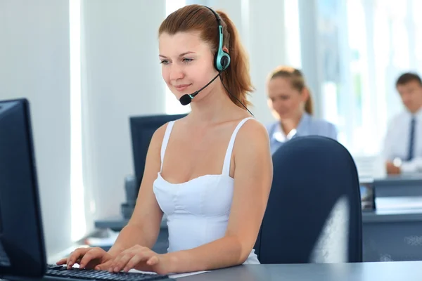 Operadora de suporte ao cliente feminina com fone de ouvido e sorrindo — Fotografia de Stock