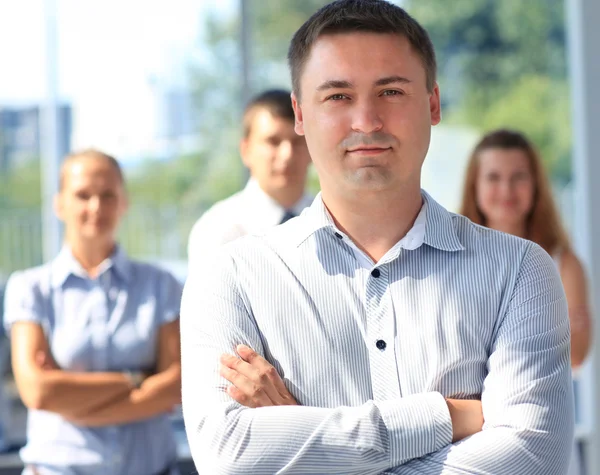 Handsome happy business man with colleagues at the back — Stock Photo, Image