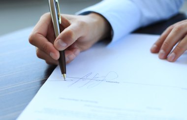 imza sığ odaklı bir sözleşme imzalayarak office masada oturan iş kadını.