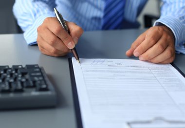 Ofis masasında oturan bir işadamı imzaya odaklı bir sözleşme imzalıyor..