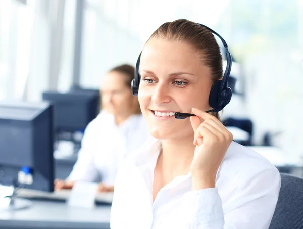Mooie jonge vrouwelijke call center operator met headset in het kantoor — Stockfoto