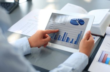 Business person analyzing financial statistics displayed on the tablet screen clipart