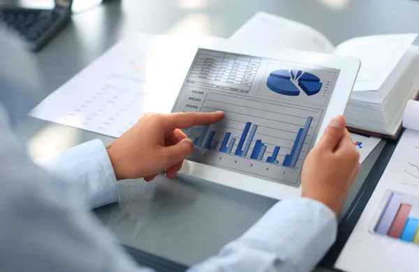 Persona de negocios que analiza las estadísticas financieras que se muestran en la pantalla de la tableta Imagen De Stock