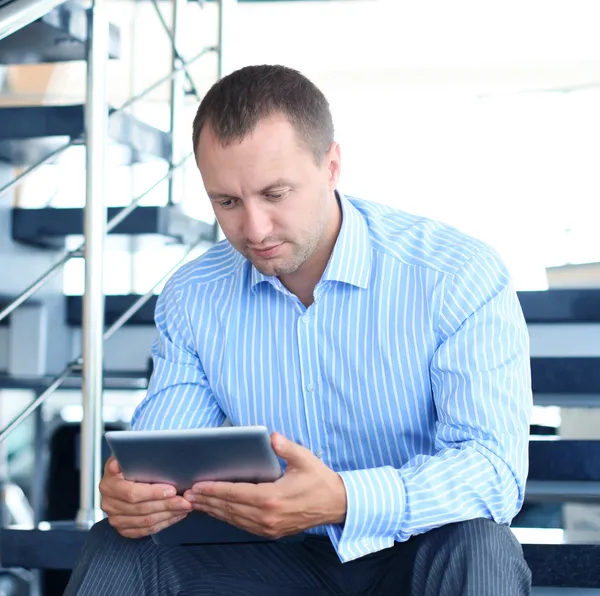 Бизнесмен сидит на лестнице с электронным планшетом — стоковое фото