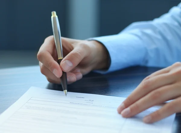 Empresária sentada na mesa do escritório assinando um contrato com foco superficial na assinatura — Fotografia de Stock