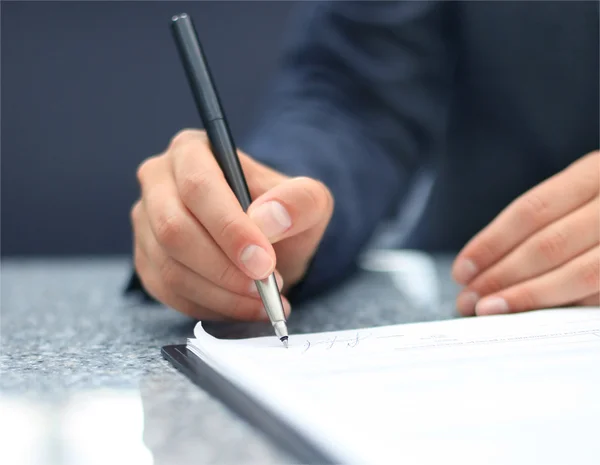 Empresária sentada na mesa do escritório assinando um contrato com foco superficial na assinatura — Fotografia de Stock