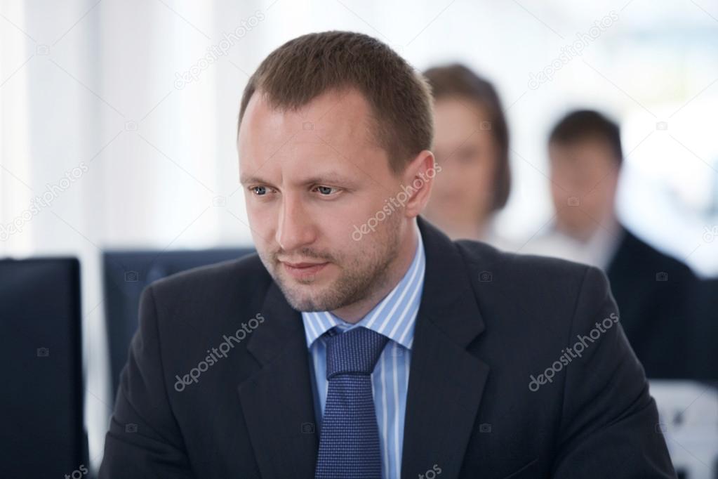 Portrait of happy business man with his colleagues in background