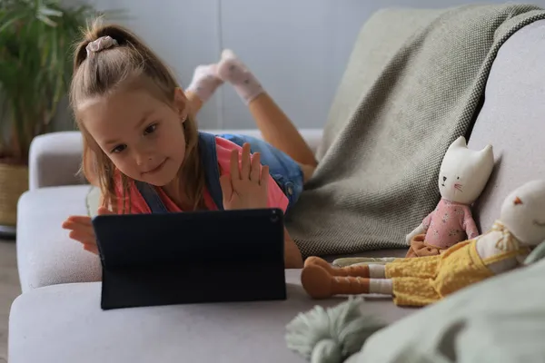Улыбающаяся Маленькая Девочка Лежащая Диване Играет Онлайн Игры Информацию Веб — стоковое фото