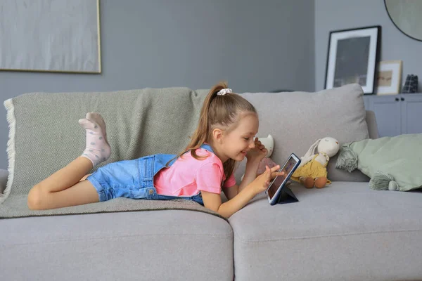 Улыбающаяся Маленькая Девочка Лежащая Диване Играет Онлайн Игры Информацию Веб — стоковое фото
