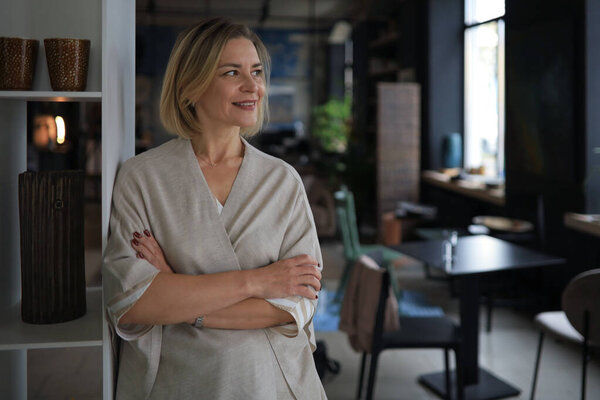 Confident stylish european middle aged woman standing at workplace, executive leader manager