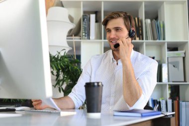 Gülümseyen genç iş adamı ofiste video görüşmesi yapıyor.