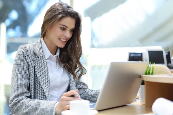 Portrait d'une jeune femme d'affaires brune utilisant un ordinateur portable au bureau. — Photo