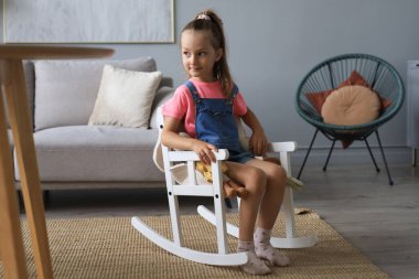 Heyecanlı çocuk evde oturma odasında otururken oyuncak oyuncaklarıyla oynuyor.