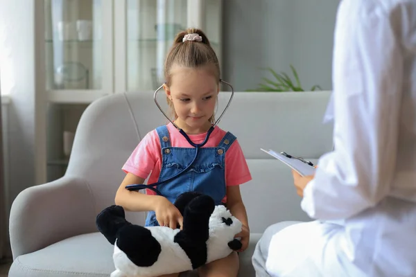 小女孩在医生那里检查 医生开玩笑地检查泰迪熊的心跳 — 图库照片
