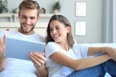 Genç bir çift, oturma odasındaki kanepede oturup internetten medya içeriğini izliyor.