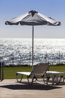 sun yakınındaki bir havuz rahatlatıcı sandalye ve şemsiye