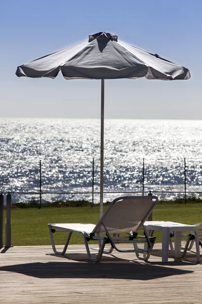 Sun umbrella and relaxing chairs near a pool — Stock Photo, Image