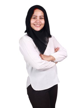 Güzel, mutlu, Asyalı Müslüman kadın kameraya bakıyor ve kollarını kavuşturup gülümsüyor.