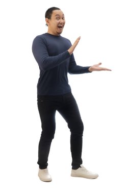 Sıradan mavi gömlekli, siyah kot ve beyaz ayakkabılı, gülümseyen, işaret eden ya da kendi tarafında bir şey sunan bir adam. Tüm vücut portresi izole edildi.