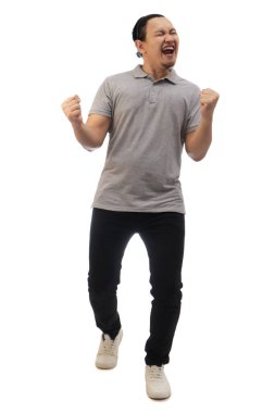 Asyalı adam gri gömlekli siyah kot ve beyaz ayakkabılı, çığlık çığlığa zaferi kutluyor, jest kazanıyor. Tüm vücut portresi izole edildi.