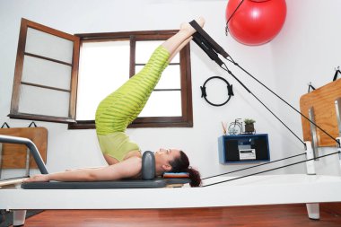 20-30 arası Latin kadın evde pilates egzersizi yapıyor. 