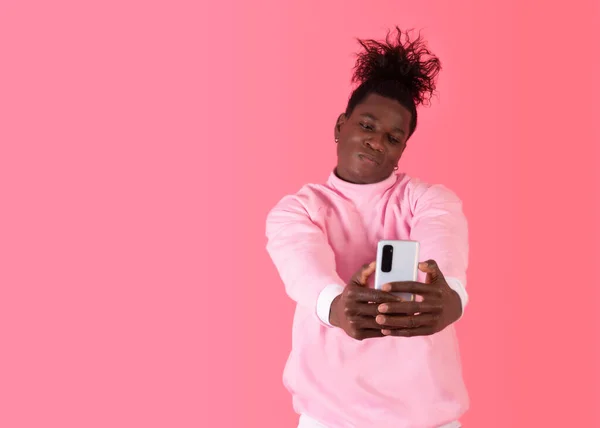 Studio shot of a young afro american taking a selfie very confident wearing a pink hoodie in pink background — ストック写真
