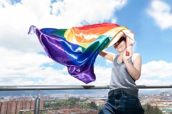 Young gay man proudly waves the LGBT flag under a sunny sky — ストック写真