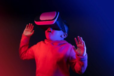 boy wearing virtual reality glasses surprised looking up with his arms open in surprise. High quality photo