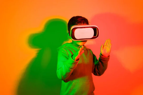Latin Boy Playing Virtual Reality Glasses Front Colored Lights Background — Stockfoto