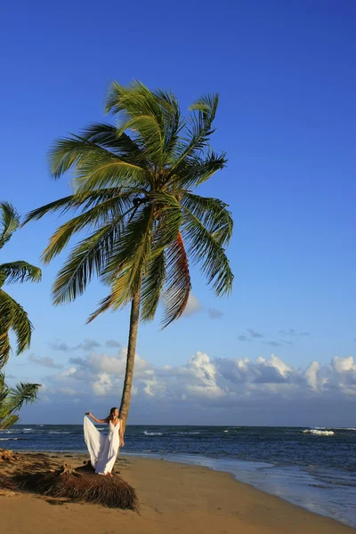 Ung kvinna i vit klänning på en strand — Stockfoto