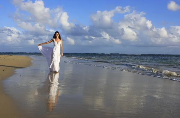 Ung kvinna i vit klänning på en strand — Stockfoto