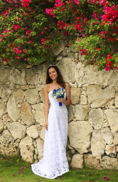 Young woman in wedding dress posing in front of the stone wall w — Stock Photo, Image