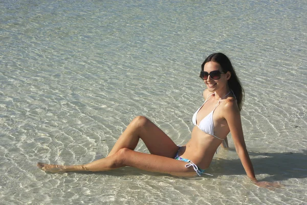 Young woman in bikini sitting in clear shallow water — Stock Photo, Image