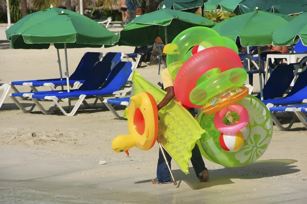 Mann geht mit Schwimmmatratzen und Ringen, Strand von Boca Chica — Stockfoto