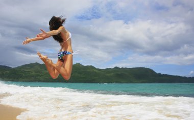 Young woman in bikini jumping at Rincon beach