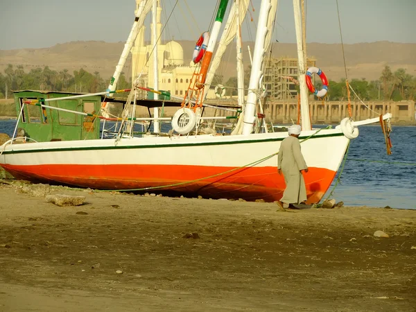 Man in traditional dress walking along felucca boat — Stock Photo, Image