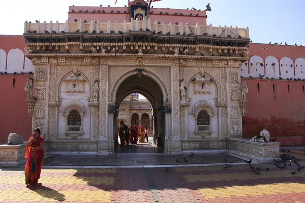 Mujer en colorido sari de pie junto a la fachada del Templo Karni Mata , — Foto de Stock