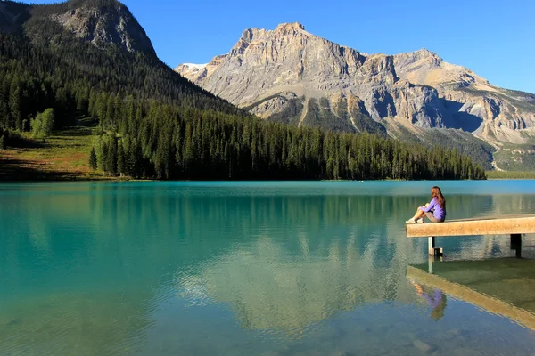 Junge Frau sitzt auf einem Steg am smaragdgrünen See, Yoho National Par — Stockfoto