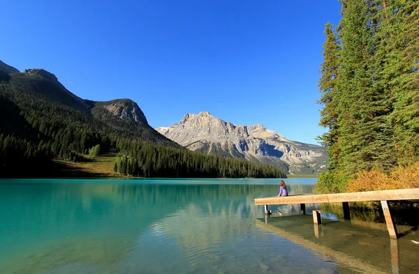 Jonge vrouw zat op een pier in emerald lake, de nationale par yoho — Stockfoto