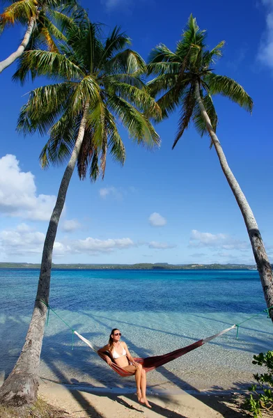 Ung kvinna i bikini som sitter i en hängmatta mellan palmerna, o — Stockfoto